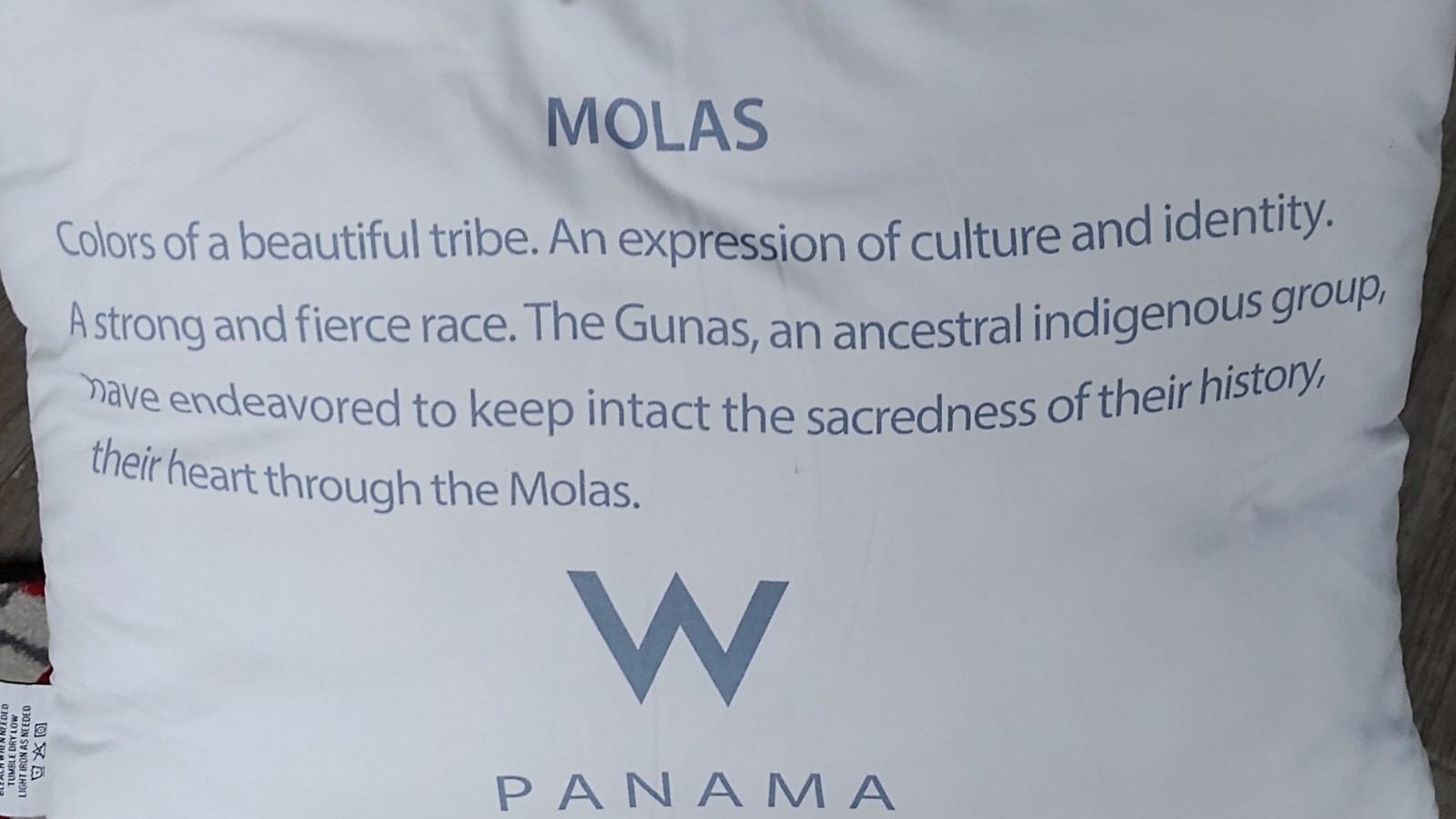 BACK OF THE PILLOW EXPLAINING THE ART OF THE INDIGENOUS GROUP IN THE COUNTRY.