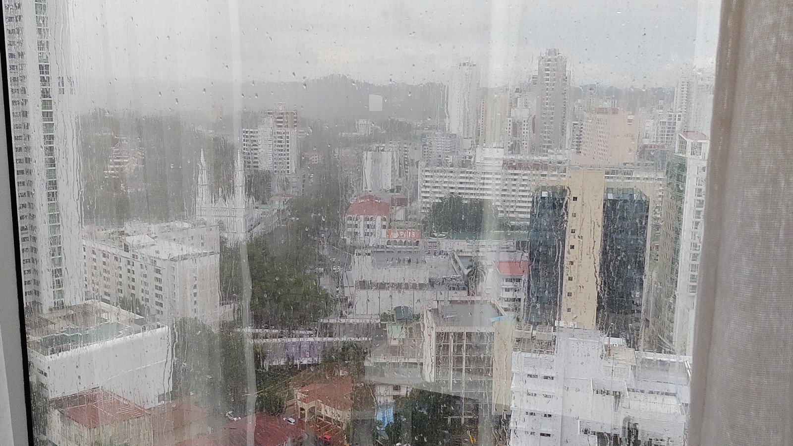 LOOKING OUT THE WINDOW ON THE POURING RAIN COVERING THE CITY.