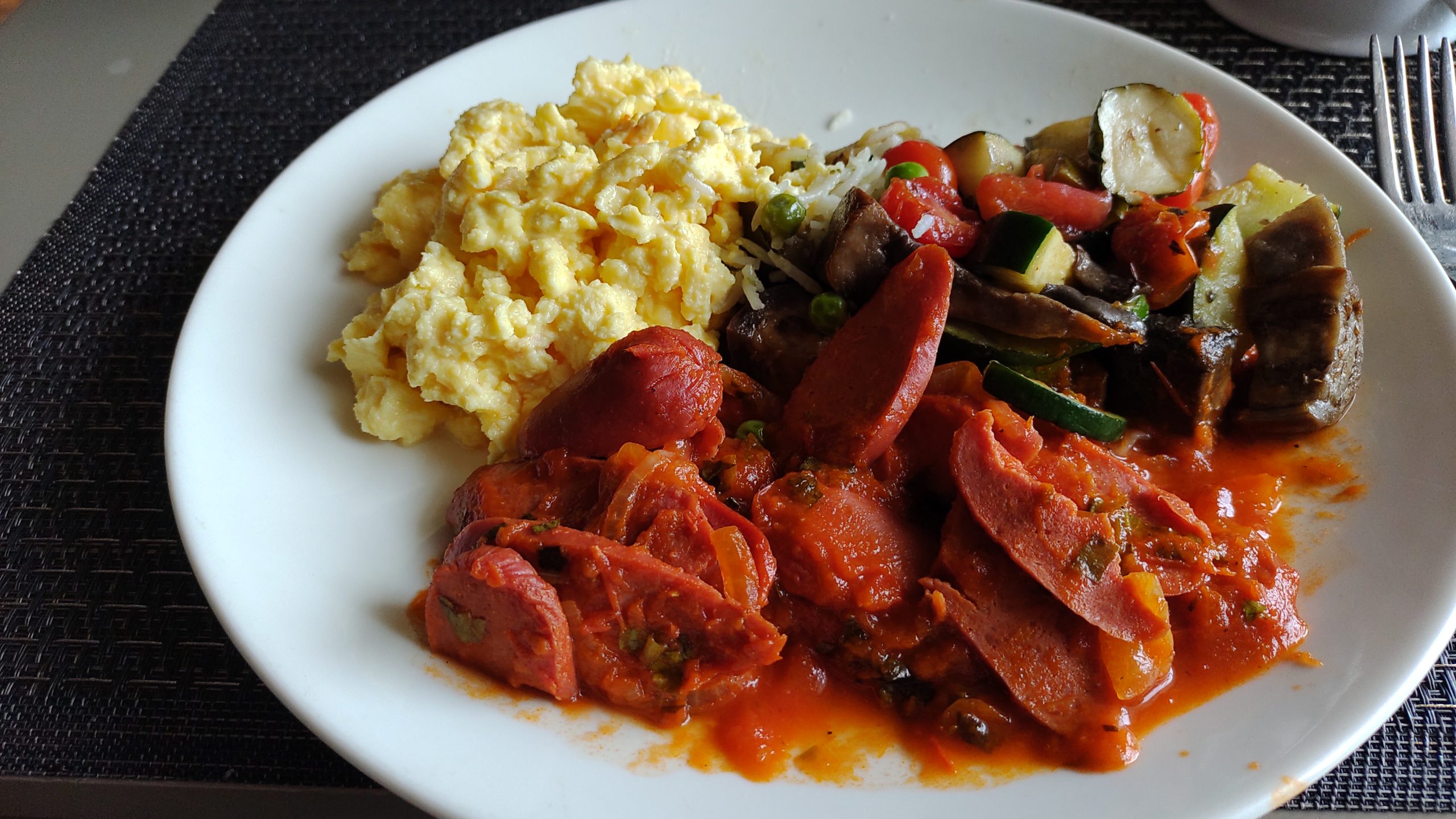 PICTURE OF A PLATE WITH STEAMED VEGETABLES, SAUSAGES  AND SCRAMBLED EGGS.
